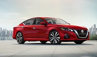 2023 Nissan Altima in red with city in background illustrating last year's 2022 model in Grainger Nissan of Beaufort in Beaufort SC