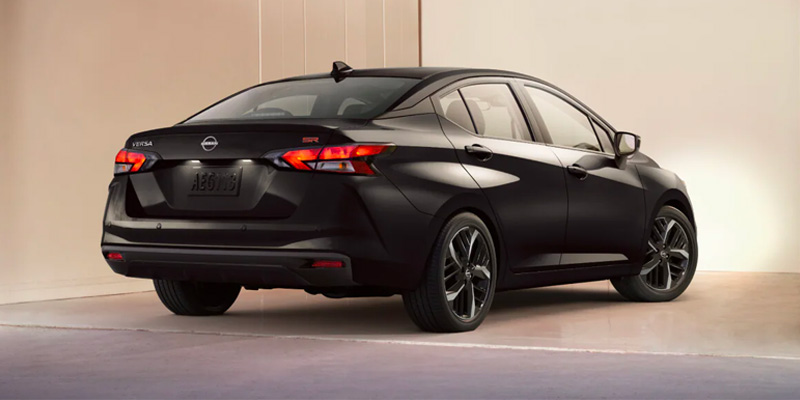 A black Nissan Versa SR viewed from the rear, showcasing its sleek design and taillights.